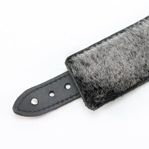 May include: A black leather collar with a gray fur trim. The collar has a buckle closure and three silver rivets.