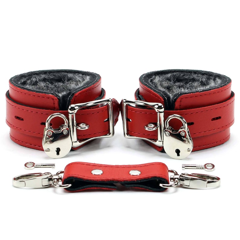 May include: Red leather and faux fur handcuffs with a silver lock and key. The handcuffs are connected by a red leather strap.