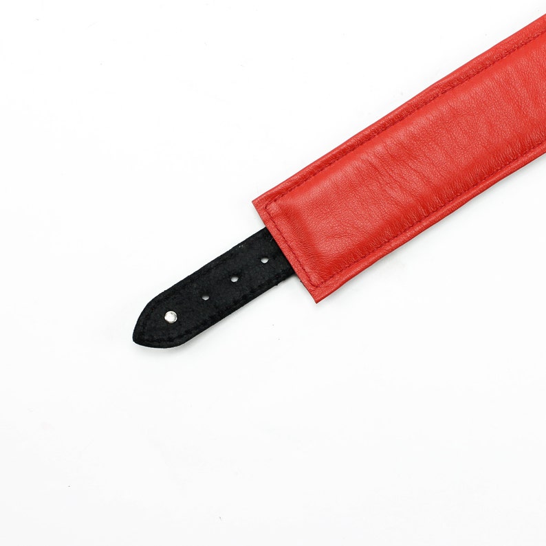 May include: A red leather collar with a black leather strap and silver buckle.