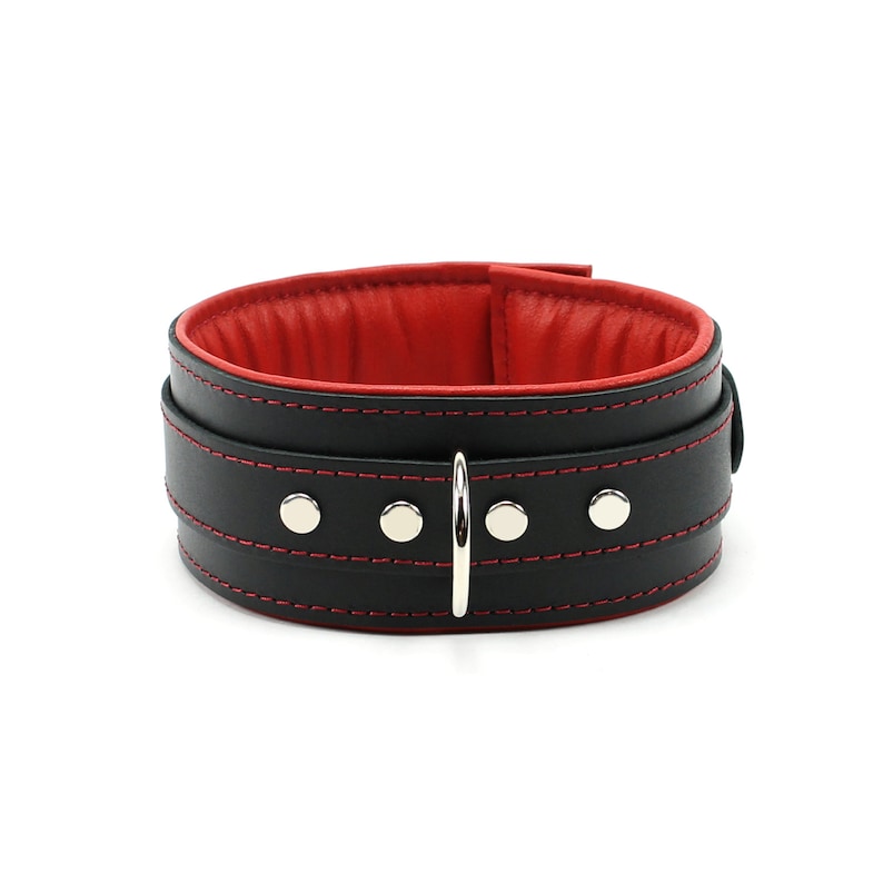 May include: Black leather collar with red stitching and silver hardware. The collar has a padded red lining.