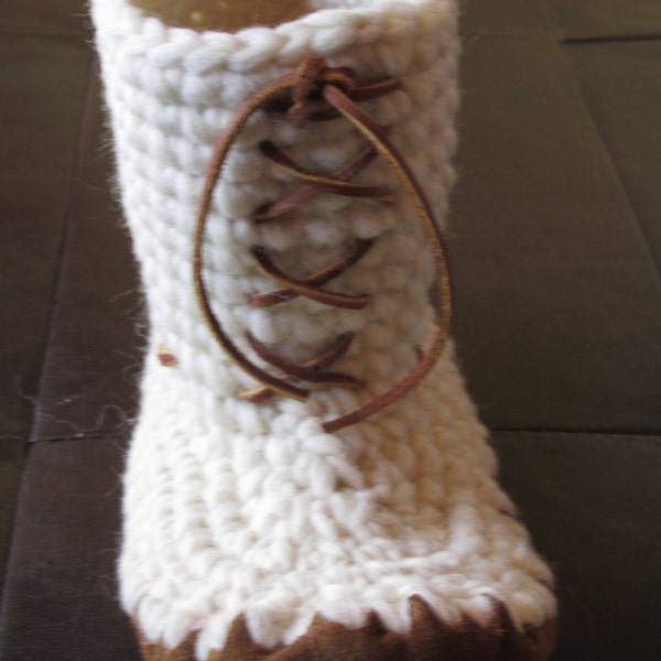 May include: White knitted boot with a brown leather lace-up closure. The boot has a brown suede sole.