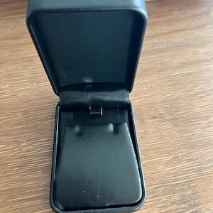 May include: A black velvet-lined jewelry box with a hinged lid. The box is open and the interior is visible.
