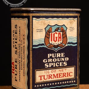 May include: A vintage metal tin of IGA brand pure ground turmeric spice. The tin is blue with gold trim and features an eagle logo with the text "IGA Brand" and "Pure Ground Spices 1/2 oz. Net Turmeric".