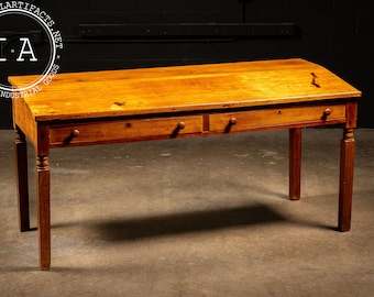 May include: A vintage wooden desk with two drawers and turned legs. The desk is made of light wood with a natural finish. The desk is in good condition with some signs of wear and tear.