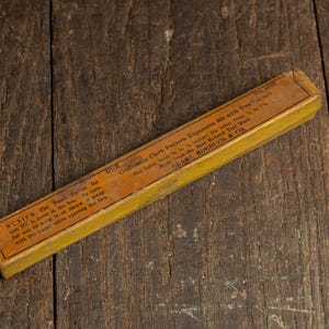 May include: An antique Craftsman Clark Pattern Expansive Bit with Two Cutters in a yellowed wooden box. The box has text that reads "Craftsman Clark Pattern Expansive Bit with Two Cutters" and "SEARS, ROEBUCK & CO." on a weathered wooden surface.