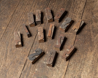 May include: A collection of vintage wooden number stamps, arranged on a weathered wooden surface. The stamps are made of wood and metal, with numbers from 1 to 9. The arrangement suggests a focus on typography and printing.