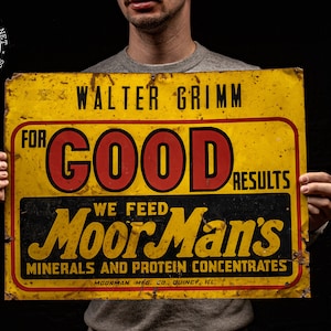 May include: A yellow metal sign with black and red lettering advertising "Moor Man's Minerals and Protein Concentrates" for good results. The sign is held by a person and has the text "Walter Grimm" at the top.