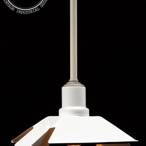 May include: Vintage industrial pendant light with a white enamel shade and a cream-colored stem. The shade has a unique, angular design with brown accents. The fixture is suspended from a metal canopy. The logo "Vintage Industrial Goods" is visible.