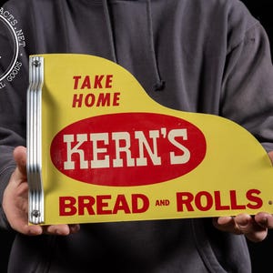May include: Yellow and red metal sign with the text "Take Home Kern's Bread and Rolls".