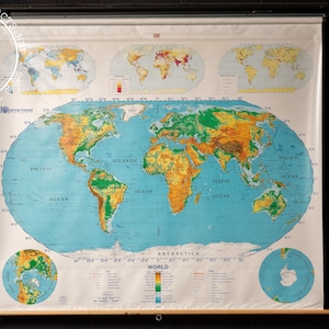 May include: A vintage world map with a blue background and green and brown continents. The map is rolled up and has a wooden dowel at the top. The map is labeled "WORLD" and has a key with different colors representing different elevations.