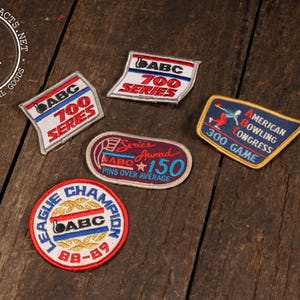May include: A collection of vintage bowling patches with various designs and text. The patches feature the text "ABC 700 SERIES", "Series Award 150 Pins Over Average", "League Champion 88-89", and "American Bowling Congress 300 Game".