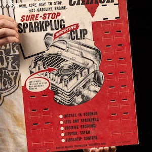 May include: A red and white cardboard package for a Sure-Stop Sparkplug Shorting Clip for gasoline engines. The package features a black and white illustration of a gasoline engine with the text "Clinton" and "Sure-Stop Sparkplug Shorting Clip".