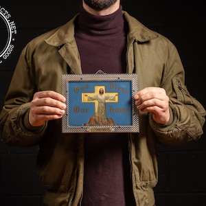 May include: A framed religious sign with a blue background and a gold cross. The sign reads "God Bless Our Home" and features a depiction of Jesus Christ on the cross.