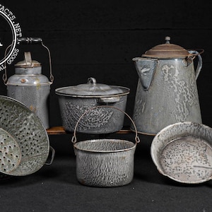 May include: Collection of vintage gray enamelware kitchen items. Includes a colander, a small pot with a handle, a covered pot, a kettle, a small pot with a handle, and a frying pan. The items have a speckled pattern.
