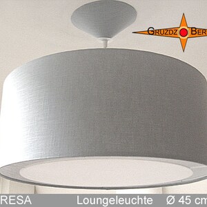 May include: A white fabric drum shade pendant light fixture with a white ceiling mount. The light fixture is 45 inches in diameter. The text "Loungeleuchte Ø 45 cm" is visible below the light fixture.