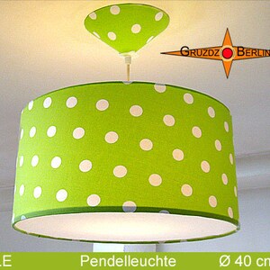May include: A green and white polka dot pendant light with a 40-inch diameter. The light has a white fabric shade and a white metal ceiling mount.