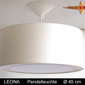 Könnte beinhalten: Eine weiße zylindrische Trommel-Pendelleuchte mit einem passenden weißen konischen Deckenbaldachin. Die Leuchte verfügt über einen runden unteren Diffusor und hat einen Durchmesser von 45 cm. Der Text LEONA Pendelleuchte Ø 45 cm ist unten sichtbar.