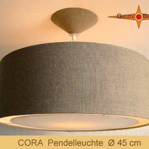 May include: A gray fabric pendant light with a white inner shade. The light is 45 inches in diameter and has a simple design. The text "CORA Pendelleuchte Ø 45 cm" is visible at the bottom of the image.