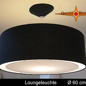 Könnte beinhalten: Eine schwarze Stoff-Trommelschirm-Pendelleuchte mit einem weißen Innendiffusor. Die Leuchte hat einen Durchmesser von 60 cm und ist mit "Loungeleuchte" beschriftet.