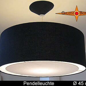 May include: A black fabric pendant light with a white inner shade. The light is 45 inches in diameter. The text "UTA Pendelleuchte Ø 45 cm" is visible below the light.