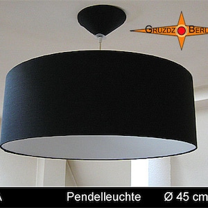 May include: A black and white pendant light with a fabric shade. The shade is 45 inches in diameter. The light is hanging from a white ceiling.
