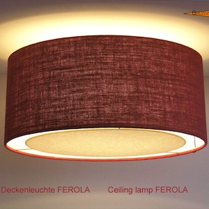 May include: A brown fabric ceiling lamp with a white inner lining. The lamp is labeled "Deckenleuchte FEROLA" and "Ceiling lamp FEROLA".