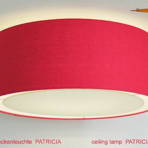 May include: A red fabric ceiling lamp with a white inner shade. The lamp is labelled "Deckenleuchte PATRICIA" and "ceiling lamp PATRICIA".