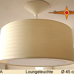 May include: A white fabric drum shade pendant light fixture with a white ceiling mount. The light fixture is labeled "Loungeleuchte" and has a diameter of 45 cm.