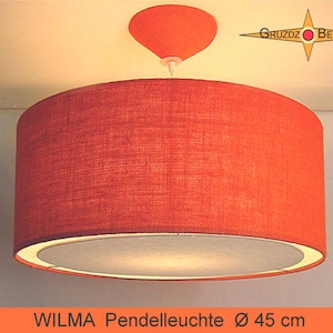 Könnte beinhalten: Eine zylindrische orangefarbene Pendelleuchte mit strukturiertem Stoffschirm und weißem Diffusor an der Unterseite. Die Deckenhalterung ist orange und konisch. Der Text GRUZDZ BERLIN und WILMA Pendelleuchte 45 cm ist sichtbar.