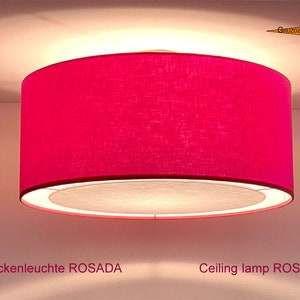 Może przedstawiać: Lampka sufitowa z różowego materiału z białym wewnętrznym kloszem. Lampa jest oznaczona jako "Lampka sufitowa ROSADA".