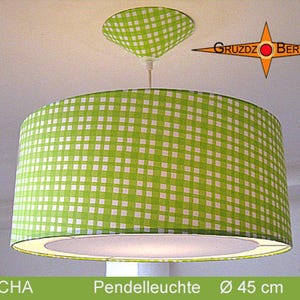 Könnte beinhalten: Eine grün-weiß karierte Pendelleuchte mit passendem Deckenbaldachin. Der Lampenschirm ist zylindrisch, mit einem Durchmesser von ca. 45 cm. Der Text "GRUZDZ BERLIN" ist sichtbar.