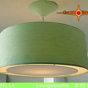 Puede incluir: Una pantalla de lámpara de tela verde con una pantalla interior blanca y una montura de techo blanca. La pantalla tiene un diámetro de 60 cm. La lámpara está etiquetada como "Isabella" y "Loungeleuchte".