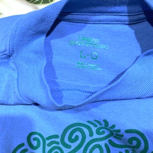 May include: A blue t-shirt with a green swirl design and the text "Urban Outfitters" and "L-G" printed on the front.