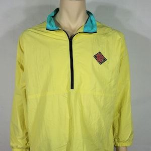 May include: A yellow windbreaker jacket with a teal collar and a black zipper. The jacket has a diamond-shaped logo with the word "Gotcha" inside.
