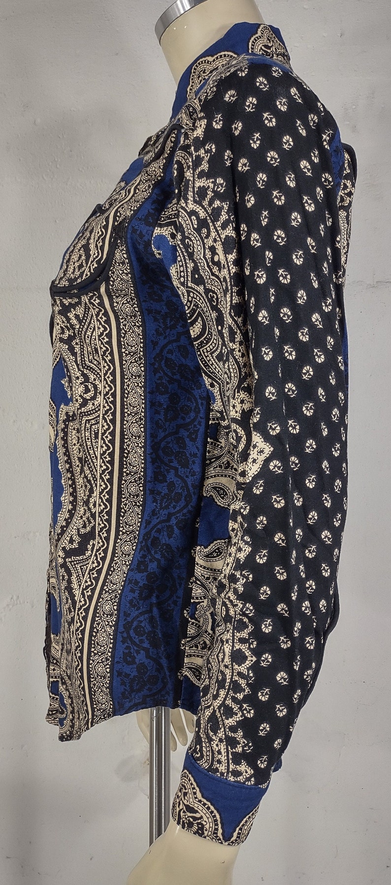 May include: A blue and cream paisley patterned long-sleeve shirt with a button-up collar.