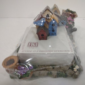 May include: A ceramic birdhouse memo holder with a blue bird, a red birdhouse, and a sign that says "Garden Welcome". The holder is designed to hold standard 3x3 inch sticky notes and 3x5 inch note paper.