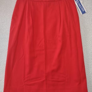 May include: A vibrant red skirt with a classic A-line silhouette. The skirt features a tailored design with pleats at the waist and a subtle sheen. A white and blue tag with the brand name "Pendleton" is attached.