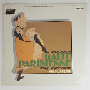 May include: A vintage record album cover featuring a woman in a yellow dress and black stockings. The album is titled "Gaite Parisienne" by Jacques Offenbach, performed by the Pittsburgh Symphony Orchestra conducted by Andre Previn.