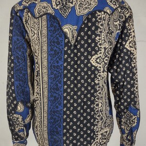 May include: A blue, black, and cream paisley patterned long-sleeve shirt with a pointed yoke in the back.