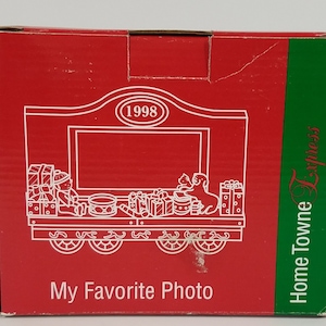 May include: Red and green cardboard box with a white illustration of a train carrying presents and two figures. The train has wheels and a sign that says "1998". The text "My Favorite Photo" and "Home Towne Express" are printed on the box.