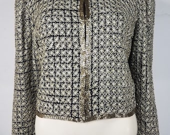 May include: A black sequined jacket with a gold floral pattern. The jacket has a front zipper closure and long sleeves.
