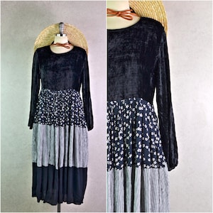 Peut inclure: Robe à manches longues avec un corsage en velours noir et une jupe à imprimé floral. La jupe présente un design plissé avec des motifs floraux blancs et rayés. La robe est présentée sur un mannequin avec un chapeau de paille.