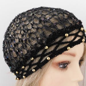 May include: Black crocheted hair net with gold-colored beads and iridescent sequins. The net is designed with a woven pattern and is worn on the head. The beads are evenly spaced along the bottom edge of the net.
