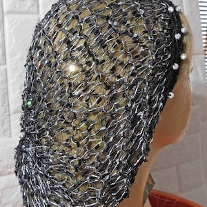 May include: Black hair net with silver and iridescent sequins. The net is gathered at the top and has a row of white beads around the edge.