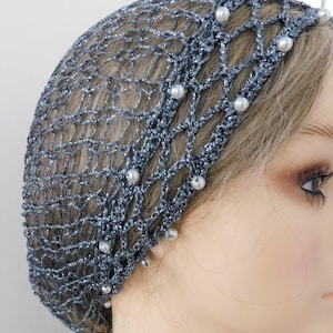 May include: A silver-blue crocheted hair net with a delicate, open weave design. The net is adorned with small, white faux pearls. The head covering is designed to be worn on the head.