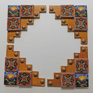 May include: A square wooden frame composed of four corner sections, each featuring decorative ceramic tiles with landscape and floral patterns. The frame is accented with small, round, metallic copper-toned studs throughout.