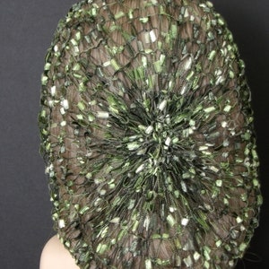 May include: A green and silver hair net with a circular shape. The net is made of a fine mesh material and has a delicate, sparkly appearance.