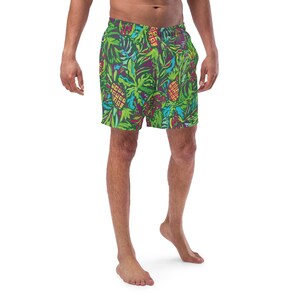 May include: Green swim trunks with a vibrant tropical pattern featuring pineapples, leaves, and flowers in shades of green, purple, and blue. The shorts have a drawstring waist and are made of a lightweight material.