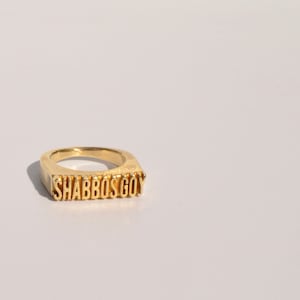 May include: A gold ring with the words "Shabbos Goy" engraved on it.