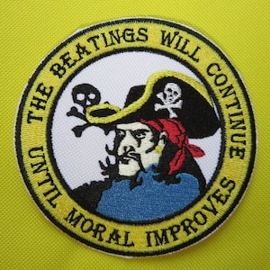 May include: A yellow embroidered patch with a pirate holding a sword and a skull and crossbones. The text around the pirate reads "The beatings will continue until moral improves."
